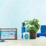 a laptop computer sitting on top of a table next to a potted plant